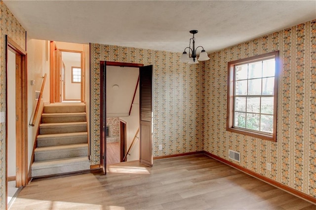 unfurnished dining area with baseboards, light wood-type flooring, visible vents, and wallpapered walls