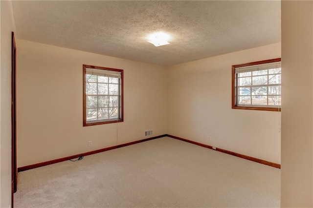 unfurnished room featuring baseboards, a textured ceiling, visible vents, and light colored carpet