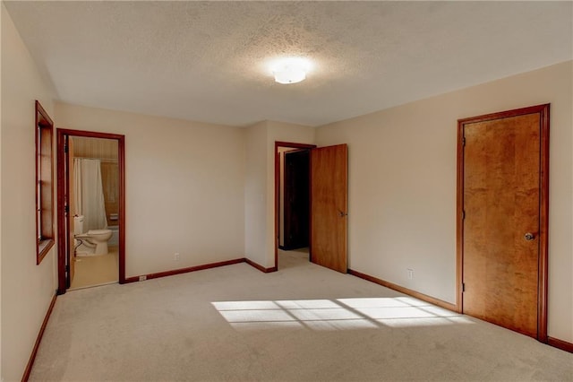 unfurnished room featuring light colored carpet, a textured ceiling, and baseboards