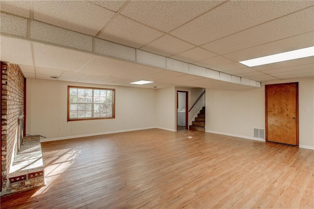 interior space featuring stairway, a brick fireplace, visible vents, and wood finished floors