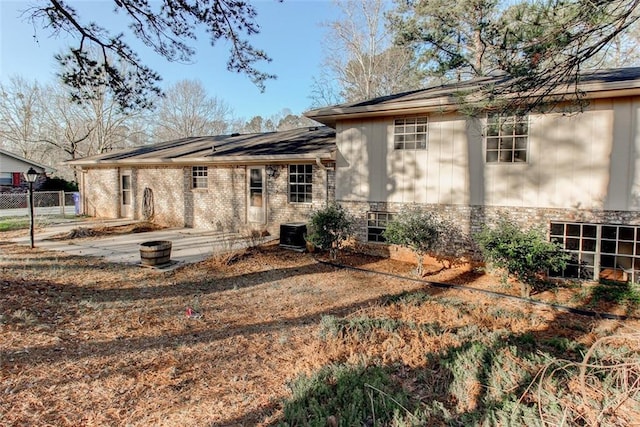 exterior space with a patio area, fence, brick siding, and central AC unit