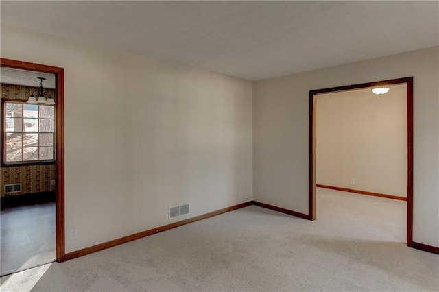 spare room featuring light carpet, baseboards, and visible vents