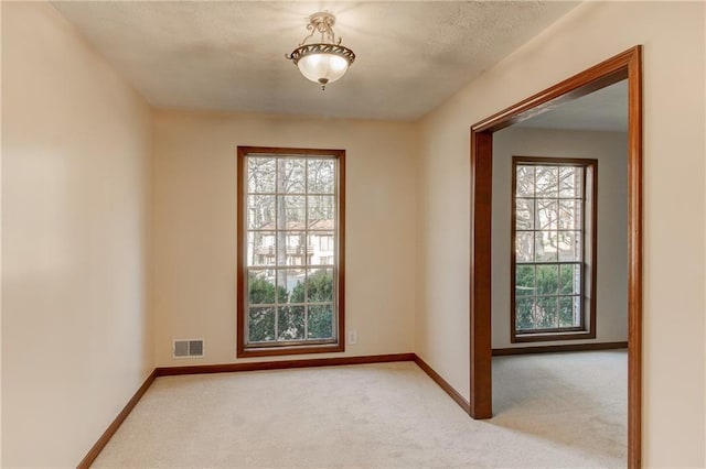 spare room featuring light carpet, baseboards, and visible vents