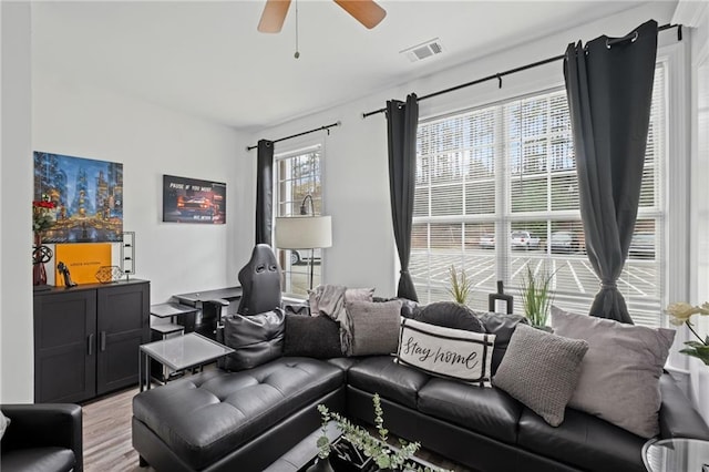 living room with light wood finished floors, visible vents, and ceiling fan