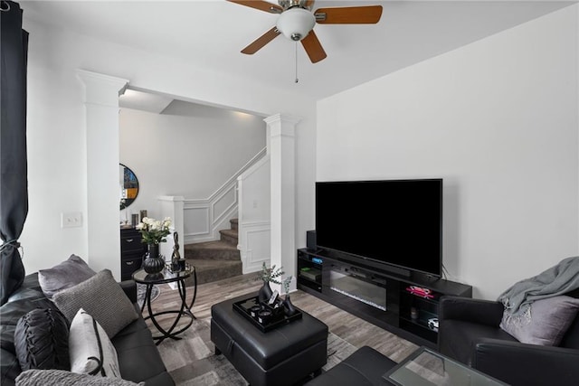 living room with ornate columns, wood finished floors, stairway, and a ceiling fan