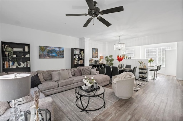 living room with wood finished floors and ceiling fan with notable chandelier