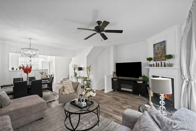 living area featuring ceiling fan with notable chandelier and wood finished floors