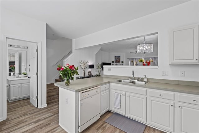kitchen with a chandelier, a peninsula, white cabinetry, dishwasher, and a sink