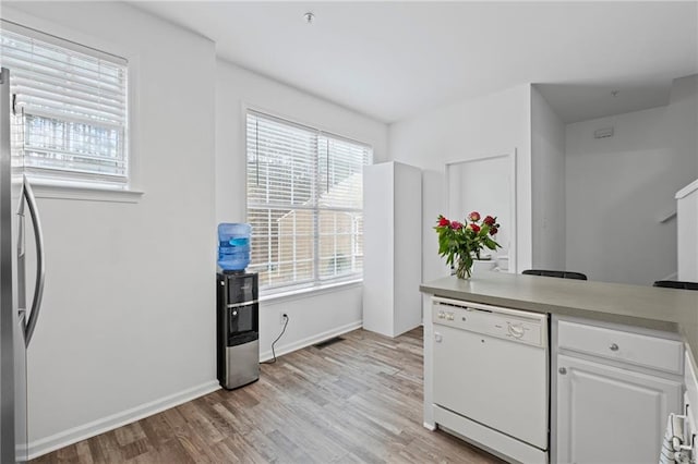 kitchen featuring white cabinetry, light wood-style flooring, stainless steel refrigerator, and white dishwasher