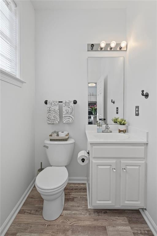 bathroom featuring toilet, wood finished floors, vanity, and baseboards