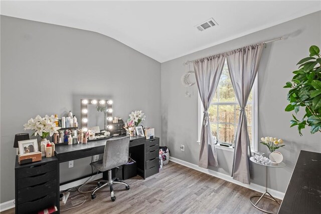 office space featuring wood finished floors, baseboards, vaulted ceiling, and visible vents
