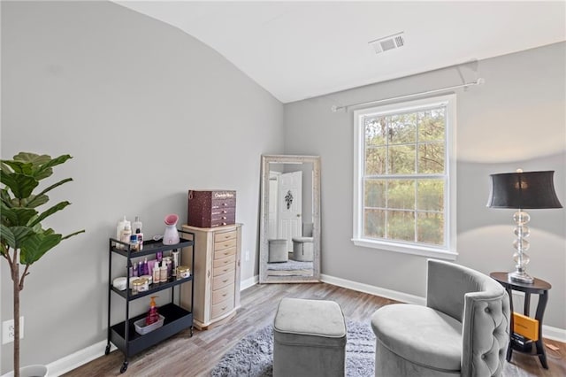 living area with wood finished floors, visible vents, baseboards, and lofted ceiling