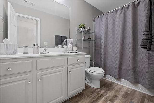 bathroom featuring visible vents, shower / tub combo, toilet, vanity, and wood finished floors