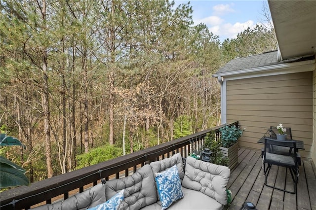 wooden deck with a wooded view and outdoor lounge area