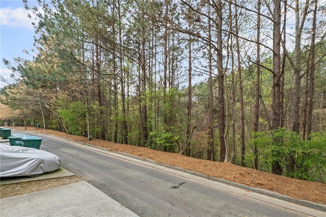 view of street with a wooded view and curbs
