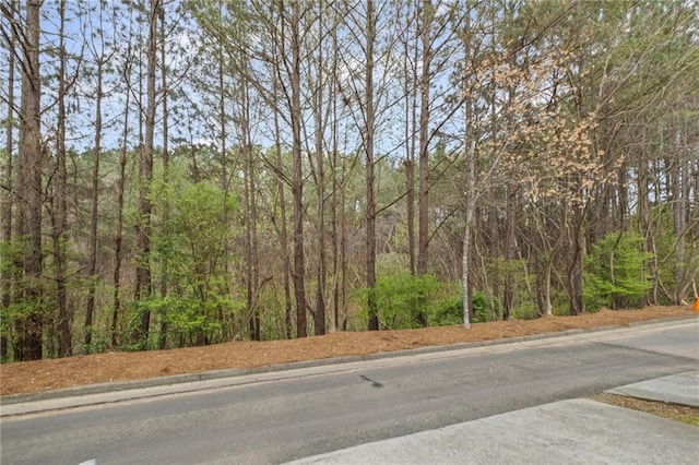 view of road featuring a forest view and curbs