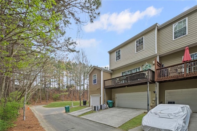back of house featuring concrete driveway, central AC, and an attached garage