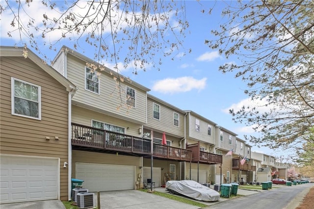 rear view of house featuring an attached garage, cooling unit, a residential view, and driveway