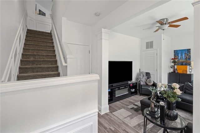 living room featuring visible vents, a ceiling fan, wood finished floors, and stairs
