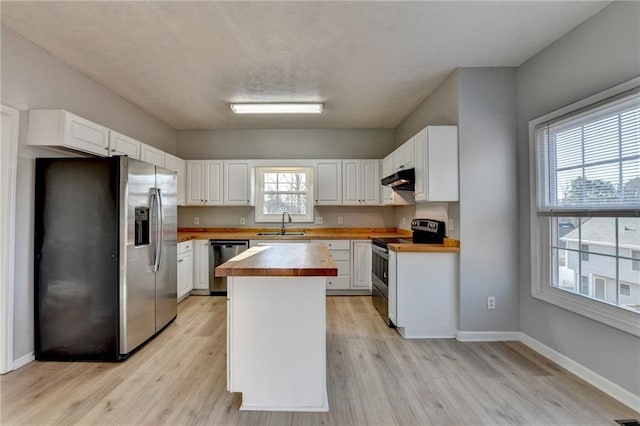 kitchen featuring stainless steel appliances, white cabinetry, a sink, wood counters, and under cabinet range hood