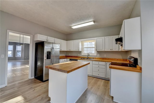 kitchen featuring wood counters, appliances with stainless steel finishes, white cabinets, and a sink