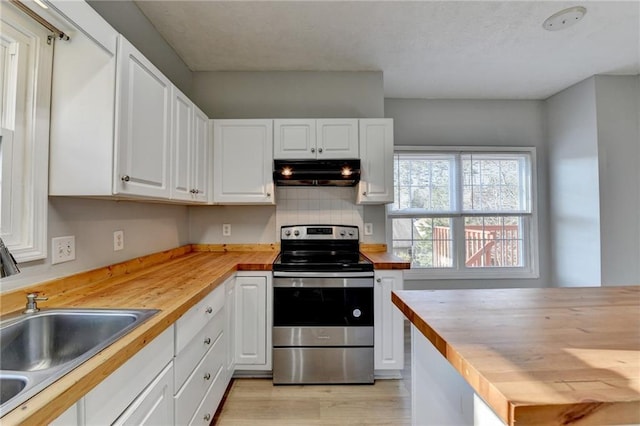 kitchen with electric range, white cabinets, under cabinet range hood, wooden counters, and a sink