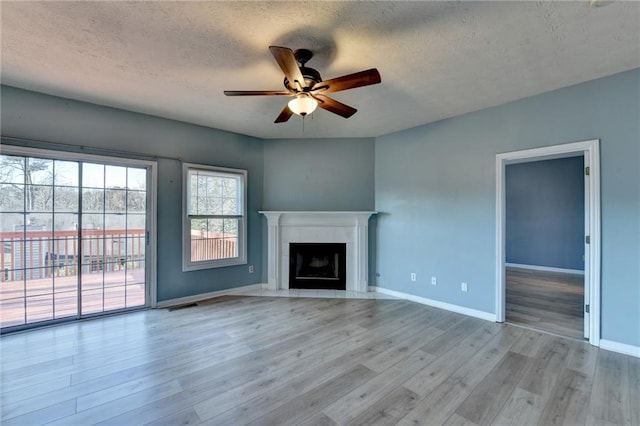 unfurnished living room with a fireplace, visible vents, baseboards, a ceiling fan, and light wood-style floors