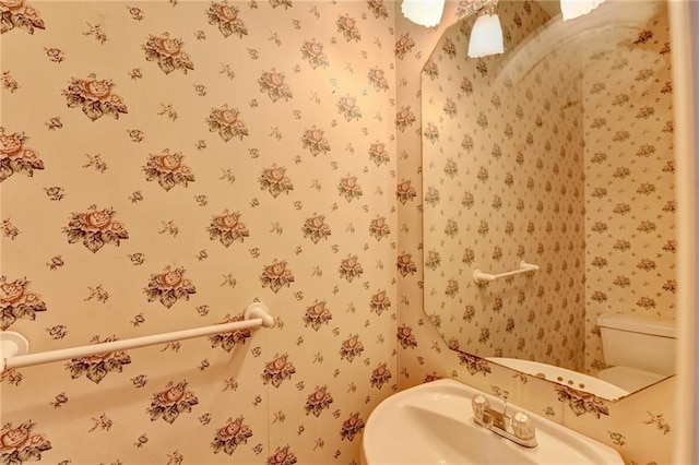 half bathroom featuring toilet and wallpapered walls