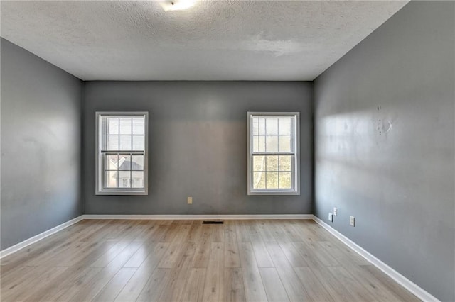 spare room with a wealth of natural light, baseboards, and wood finished floors