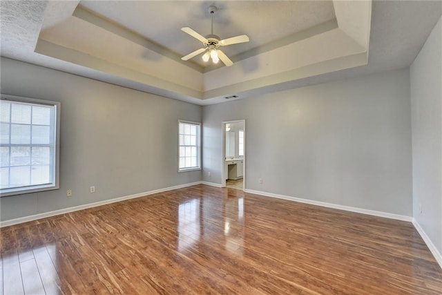 spare room with a tray ceiling and wood finished floors