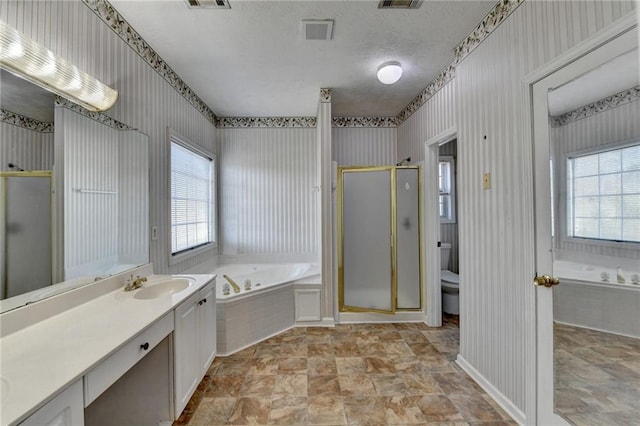 full bathroom with visible vents, a wealth of natural light, a shower stall, and vanity