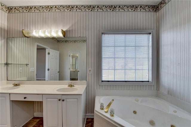 bathroom with a jetted tub, wallpapered walls, double vanity, and a sink