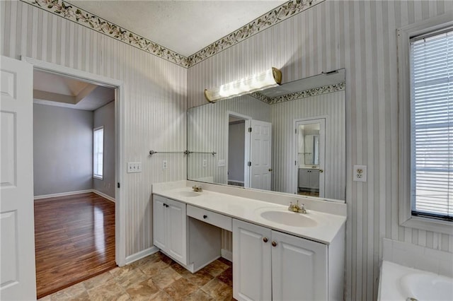 bathroom with wallpapered walls, baseboards, and a sink