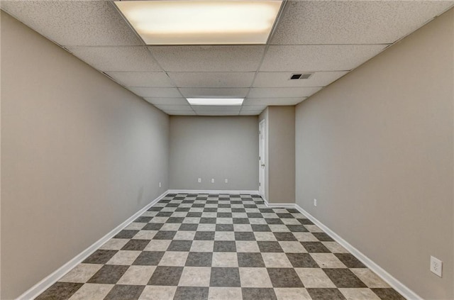 finished basement featuring baseboards, dark floors, visible vents, and a drop ceiling