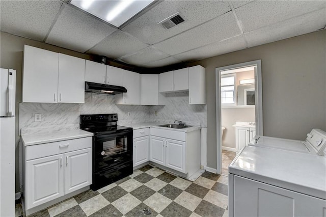 kitchen featuring under cabinet range hood, a sink, washer and dryer, black electric range oven, and light floors