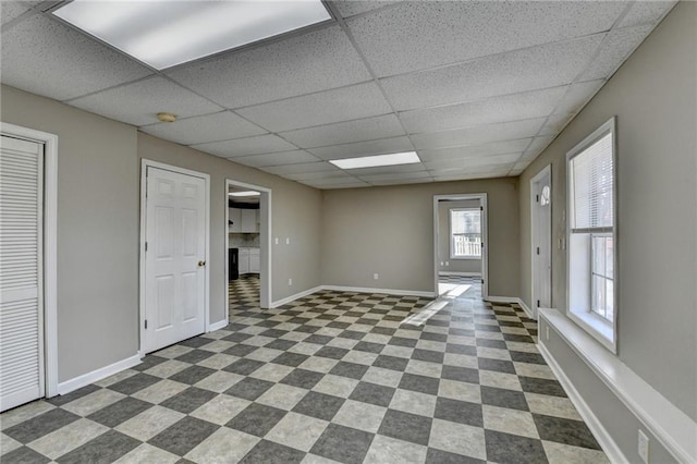 spare room with dark floors, a paneled ceiling, and baseboards