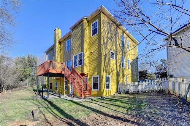 back of house featuring a lawn, a chimney, stairway, fence, and a deck