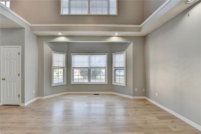 unfurnished room with baseboards, wood finished floors, and a healthy amount of sunlight