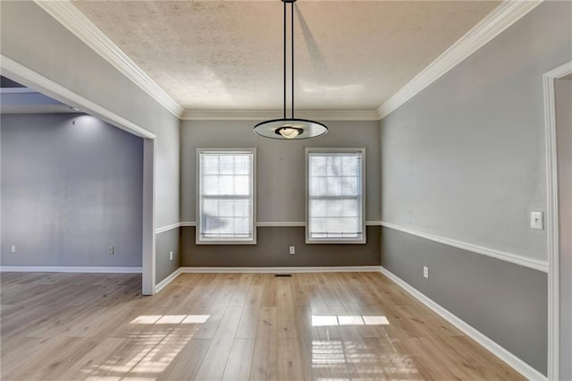 unfurnished dining area with ornamental molding, a textured ceiling, baseboards, and wood finished floors