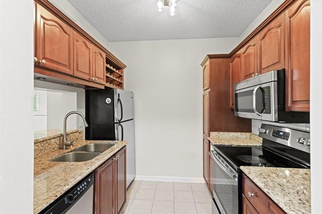 kitchen with light stone countertops, sink, stainless steel appliances, and a textured ceiling