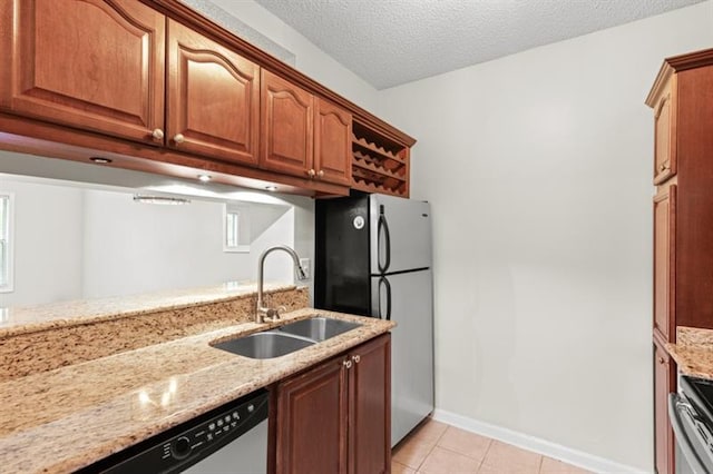 kitchen featuring sink, light stone counters, a textured ceiling, light tile patterned floors, and appliances with stainless steel finishes