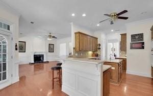 kitchen with a kitchen bar, ceiling fan, kitchen peninsula, plenty of natural light, and light wood-type flooring