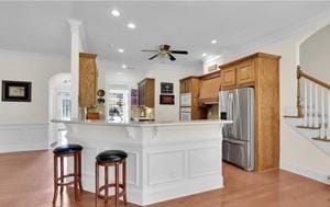 kitchen with ornamental molding, stainless steel fridge, kitchen peninsula, and a breakfast bar area