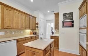 kitchen featuring sink, a center island, ornamental molding, white appliances, and decorative backsplash