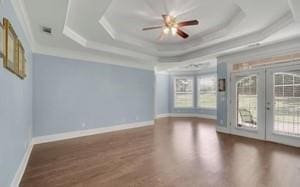 unfurnished room with a raised ceiling, ornamental molding, dark hardwood / wood-style floors, and french doors