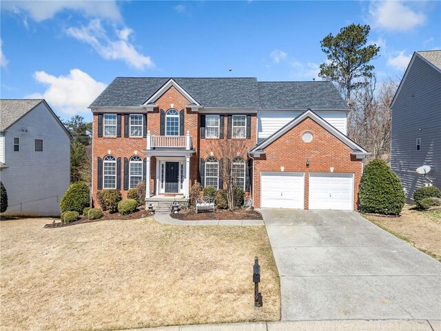 view of front of home with driveway, brick siding, a balcony, and a front yard