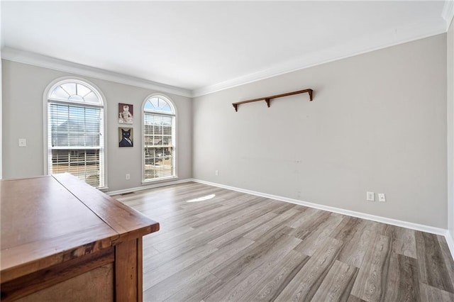 interior space with baseboards, light wood-style floors, and ornamental molding