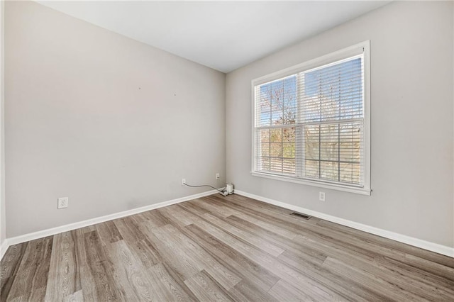 spare room featuring visible vents, baseboards, and wood finished floors