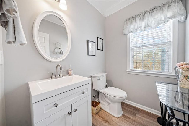 half bathroom featuring crown molding, baseboards, toilet, wood finished floors, and vanity