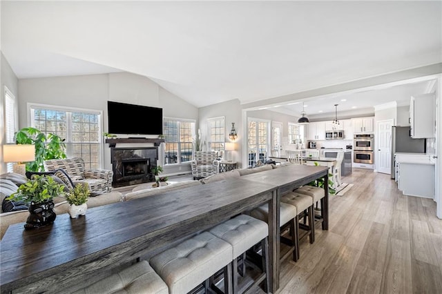 dining area featuring vaulted ceiling, recessed lighting, a fireplace, and light wood-style floors